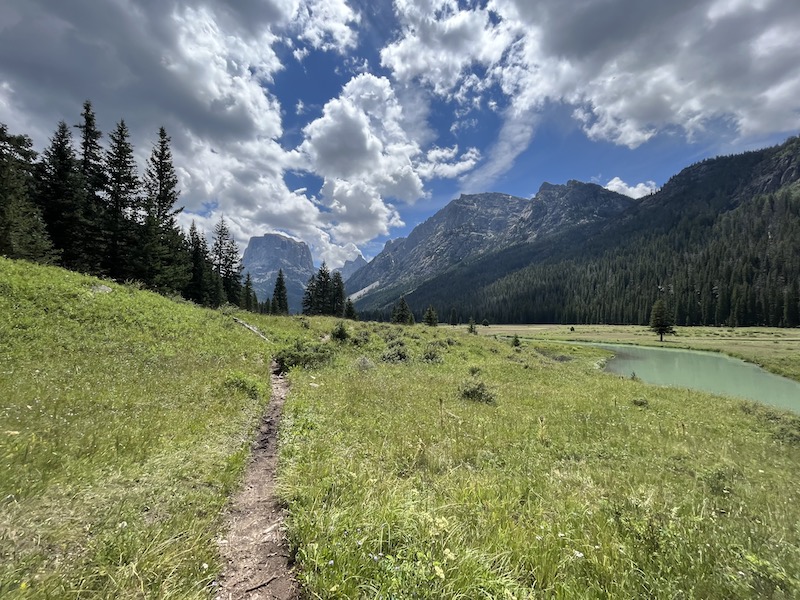 Imagen de un camino que serpentea junto a un río en un valle. Flat Top Mountain está en el fondo.